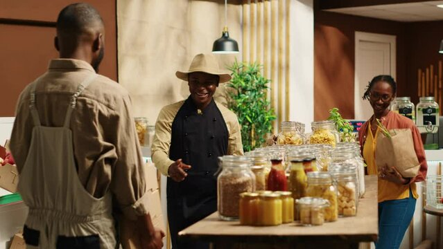 African american supplier giving fresh produce in crates to merchant, working on restocking merchandise with freshly harvested goods. Farmer and vendor collaborating on supplying store. Camera A.