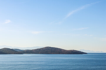 Sea, mountains and blue sky over horizon in the morning. Tranquil seascape and coastal nature concept.