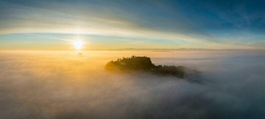 Aerial view of the Hegau volcano Hohentwiel with the upper fortress ruins as a silhouette at sunrise, rising out of the fog during an inversion, district of Constance, Baden-Wuerttemberg, Germany
