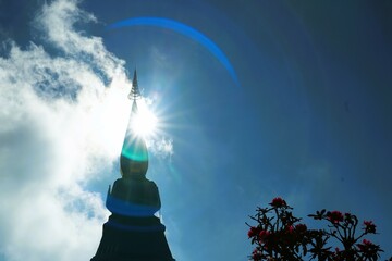 The sun shines down over the top of the pagoda.