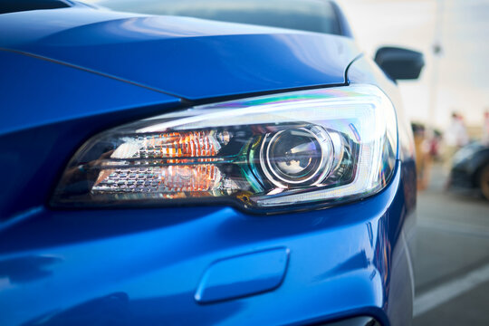 Berlin, Germany - August 20, 2022: Subaru Impreza WRX Sti detail shot. Headlight of blue metallic car shot closeup over out of focus background with copyspace.