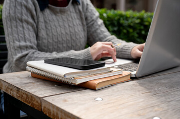 A woman using her laptop computer at a table outdoors. remote job, people and wireless technology
