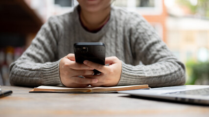 A cropped shot of a woman using her smartphone while sitting at her work desk.