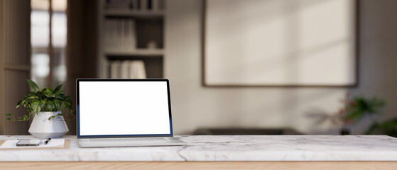 Close-up image of a white-screen laptop mockup on a white marble tabletop in a modern room.