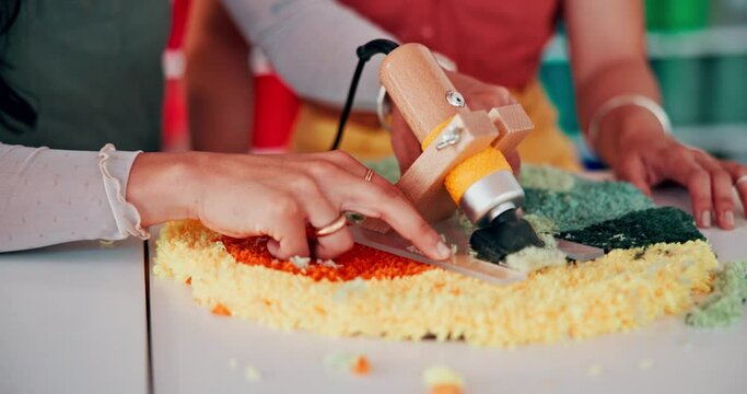 Hands, team or tufting with carpet trimmer, design or shave textile together at table. Rug, carver or closeup of professional with fabric, tools or electric machine to craft in manufacturing workshop
