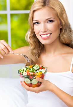 Portrait image - happy smiling young blond blonde woman with vegetable salad at home house, indoors. Healthy eating, vegetarian, keto ketogenic diet concept.