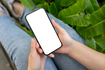 A woman using her smartphone while relaxing in a green garden. A white-screen smartphone mockup.