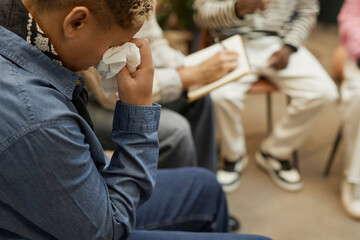 Side view portrait of person crying during emotional therapy session and wiping tears with tissue, copy space