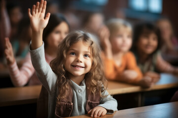 Happy little student girl raising hand up to answer. School children in classroom at lesson....