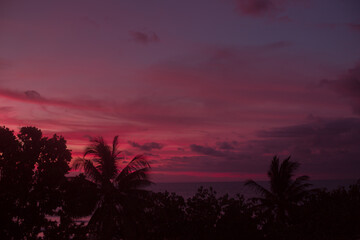 Bright colored sunset over the ocean. Pink red sky and purple clouds after sunset over the island. Beautiful natural background