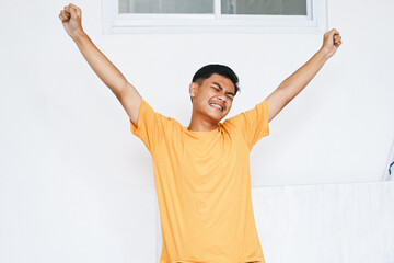 Happy Asian teenage guy with braces, stretching his back at home