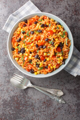 Delicious authentic Mexican tomato rice with black beans, onions and corn close-up in a bowl on the table. Vertical top view from above