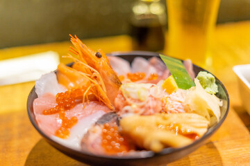 a delicious sashimi donburi, featuring an array of fresh, colorful raw fish slices like tuna, salmon, and yellowtail beautifully arranged atop a bed of fluffy white rice. The dish is garnished