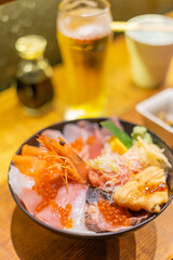 a delicious sashimi donburi, featuring an array of fresh, colorful raw fish slices like tuna, salmon, and yellowtail beautifully arranged atop a bed of fluffy white rice. The dish is garnished
