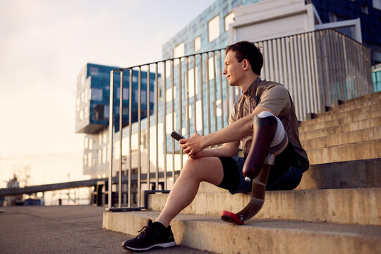 Man wearing a prosthetic running blade checking his phone outside - Powered by Adobe