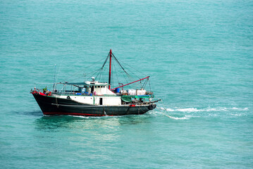 Fishing boat sailing through calm waters near Vietnamese sea coast.