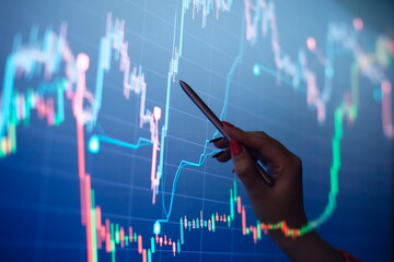 Businesswoman manually drawing a diagram on a touch screen interface. Stock market concept