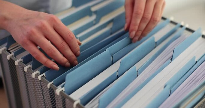 Female office worker takes documents in blue folder from box