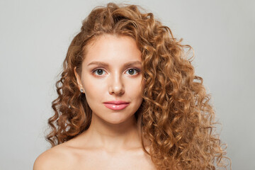 Healthy redhead female model with long frizzy ginger hair and clean soft fresh skin posing on white background. Studio fashion beauty portrait of young woman