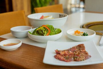 Japanese yakiniku (grilled meat) served alongside a bowl of refreshing cold noodles. The yakiniku features tender, perfectly grilled slices of meat with a caramelized glaze