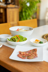 Japanese yakiniku (grilled meat) served alongside a bowl of refreshing cold noodles. The yakiniku features tender, perfectly grilled slices of meat with a caramelized glaze