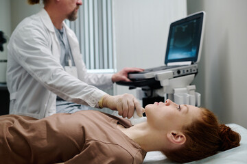 Young female patient lying in front of camera in medical office during ultrasound diagnostics being...