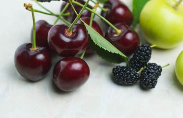 Red cherries and fruits on white mar