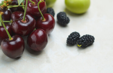 Red cherries and fruits on white mar