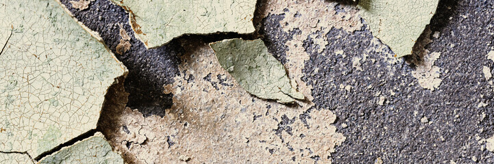 Peeling paint on the wall. Panorama of a concrete wall with old cracked flaking paint. Weathered rough painted surface with patterns of cracks and peeling. Panoramic texture for background and design.