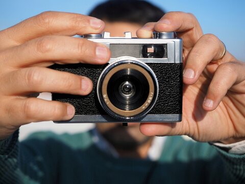 Unrecognizable man taking a picture on a retro photo camera outdoors 