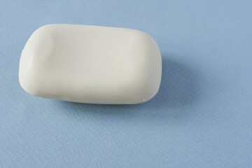 A piece of white soap on a blue background. Detergent. Creamy soap.