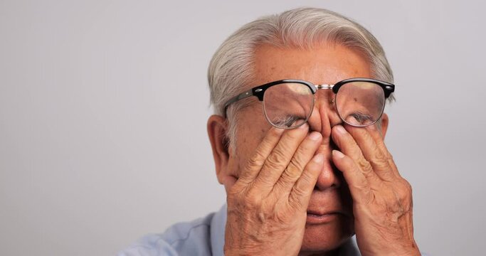 Asian old man was rubbing his eyes, tired of staring for a long time. Elderly man is suffering from eye strain due to his long-time looking at the digital tablet.
