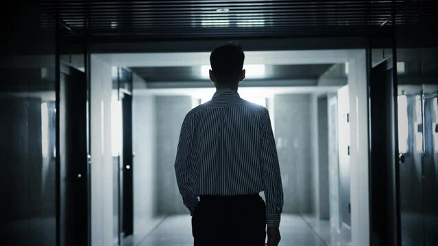 Businessman walking along the dark corridor