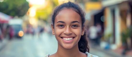 A happy young girl with a smile on her face, standing on a city street, her hair blowing in the wind.