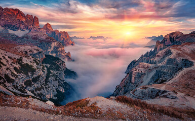 Colorful cliffs at sunrise in Tre Cime Di Lavaredo National Park. Thick fog spreads of mountain...