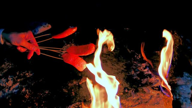Image of cooking sausage over fire in nature. close-up 4K shot. Life and nutrition in nature
