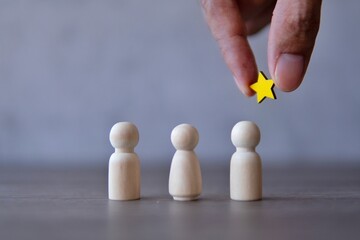 Hand holding a star over the team. Awarding, appreciation and reward for employees concept.
