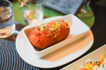 Gourmet croquette garnished with sprouts on a white dish.