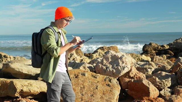 Young senior marine biologist takes notes digital tablet, boy is analyzing sea water in the mediterranean sea. Study of scientific statistics.