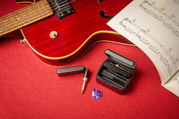 Guitar wireless system, with radio transmitter and receiver, with a red hollow jazz guitar.