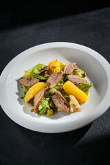 Duck and orange salad closeup with walnuts, on a bed of mixed greens, drizzled with a balsamic reduction