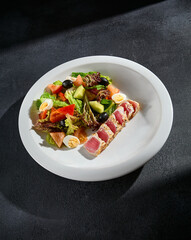 Seared tuna Niçoise salad on a modern dark background; a fresh and gourmet presentation for health-conscious foodies