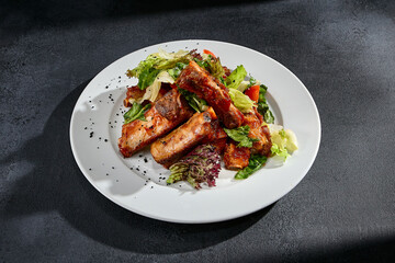 BBQ ribs with a mixed salad garnish on a white plate