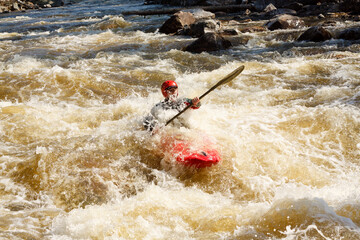 Adventurous Man in Red Kayak in Turbulent River with Lush Forest and Rocks