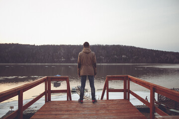 Frozen Lake Man Contemplating the Serene Beauty of a Winter Afternoon on a Wooden Dock