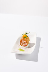 Crunchy crabmeat cannoli on a sleek white dish with a citrus accent, perfect for refined appetizers and modern cuisine