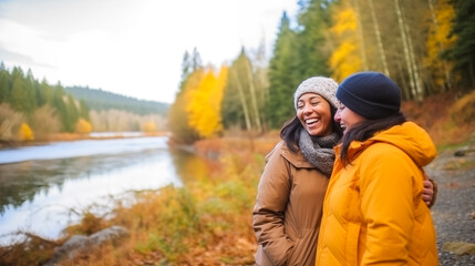Two middle-aged women hiking near a river in an autumn forest.