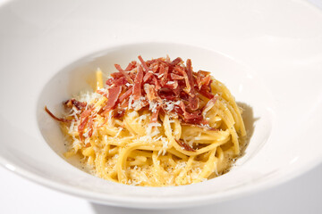Classic Italian Carbonara Pasta with Bacon, Cheese, and Egg Yolks, Served in a White Bowl for a Traditional Culinary Experience