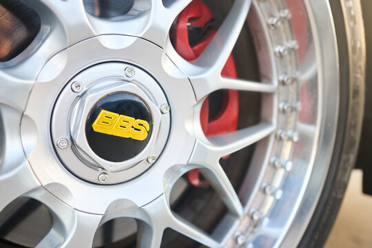 Berlin, Germany - August 20, 2022: BBS badges logo emblem on BBS alloy wheel plug and red brake caliper selective focus close up.