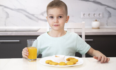 Happy child eating fast food at home chicken nuggets. Boy eats junk food at home.